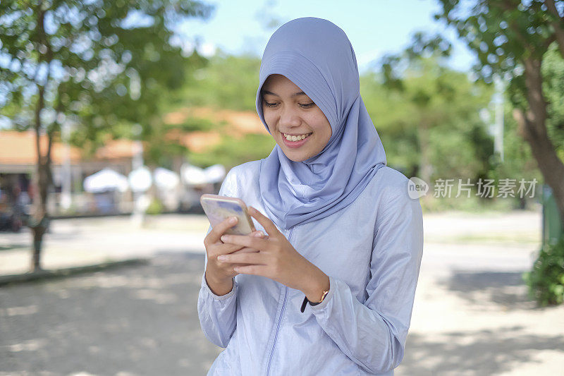 微笑的印尼穆斯林妇女用手机应用程序叫出租车