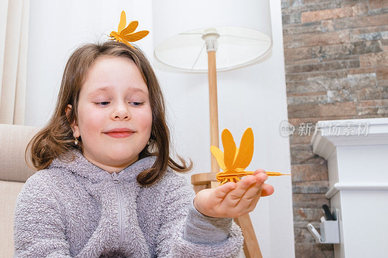 一个7岁的白人女孩正在用木制材料制作蜻蜓玩具。