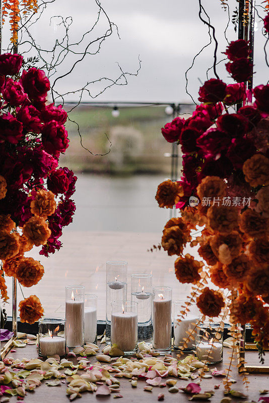 照片墙与码头，拱门装饰粉红色，橙色的花玫瑰，蜡烛。宴会区，大厅，生日派对的时尚装饰。餐厅活动。豪华婚礼的婚宴。