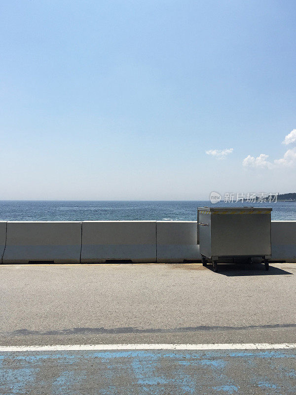 海岸线上的垃圾桶，混凝土地板，大海和天空的背景