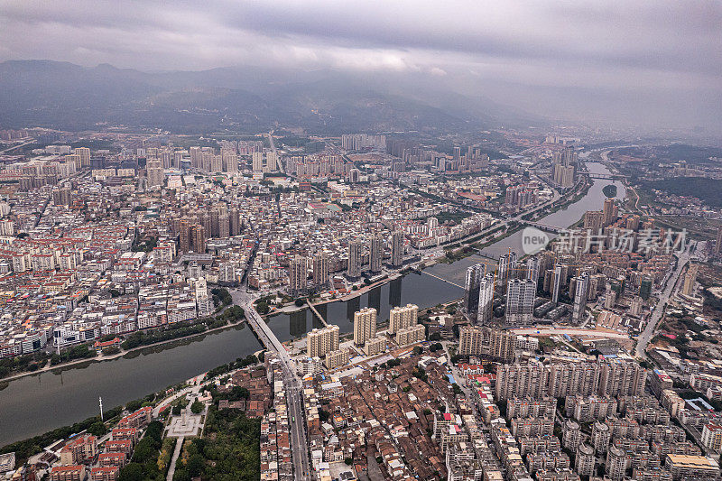 多云天，有河流的城市中人口密集的建筑物鸟瞰图