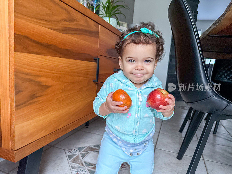 女婴抱着水果在屋子里走来走去