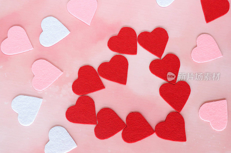 红心形状的特写图像，由红心被粉红色和白色的心包围，情人节装饰，斑驳的粉红色背景，抬高的视图，情人节和浪漫的概念