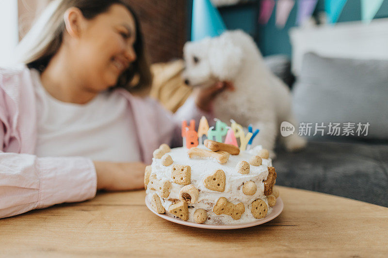 快乐的年轻女子在家里为她的狗庆祝生日