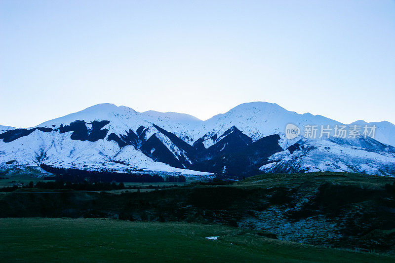 日落时，新西兰西海岸寒冷的山脉被雪覆盖