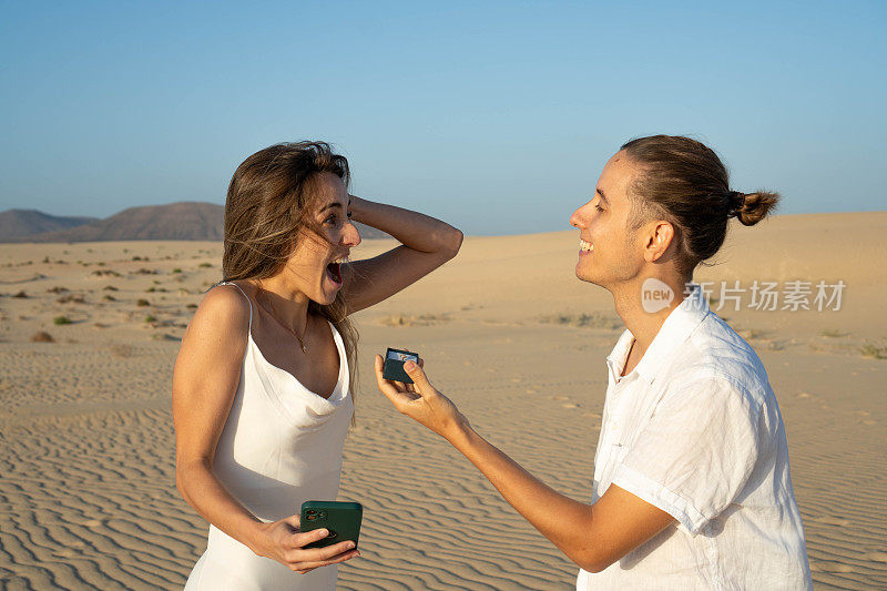 在宁静的沙漠风景中，快乐的女人被伴侣的求婚惊呆了