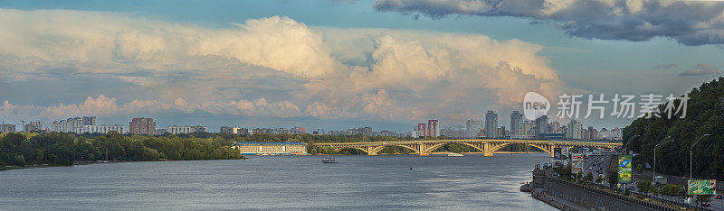 夕阳映照在基辅第聂伯河上的地铁大桥上，天空中有如画般的雷云。