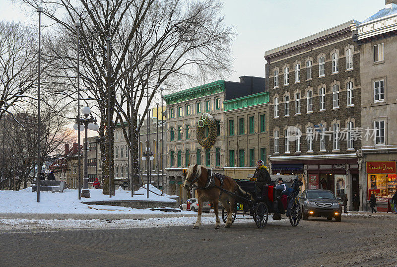 在一个冬天的晚上，游客们乘坐马车游览魁北克老城。