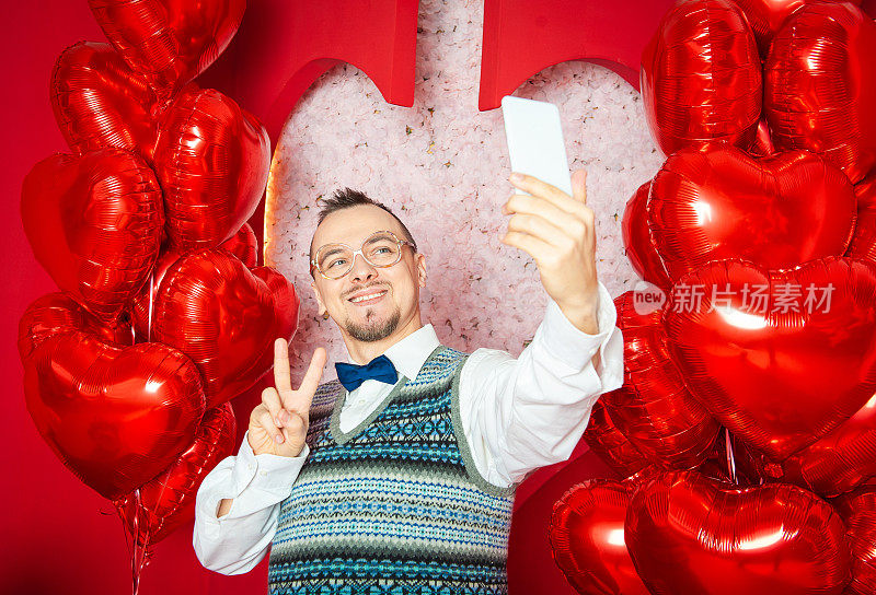 有趣的快乐大胡子复古风格的男人与红色心形气球制作自己的情人节照片