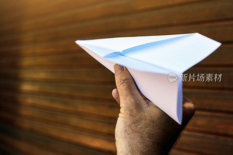 男人的手即将发射一架纸飞机，用递减的视角和复制空间