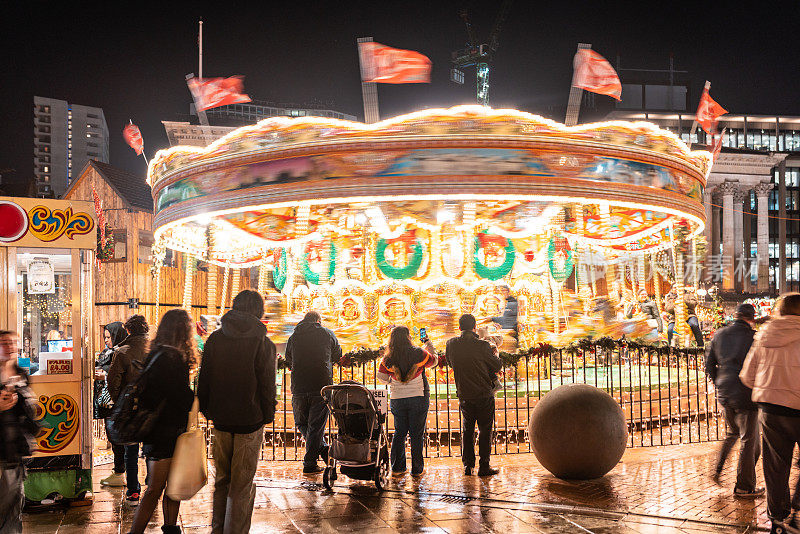 圣诞市场的场景，人们和旋转木马在晚上