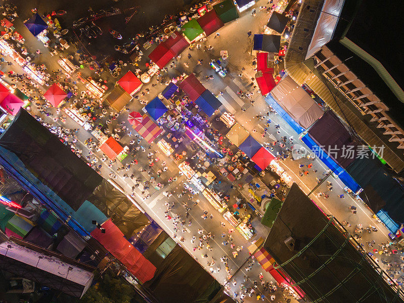 夜市庙会和当地夜市的游乐园鸟瞰图。人们走在街上，五颜六色的帐篷在曼谷市，泰国。零售商店