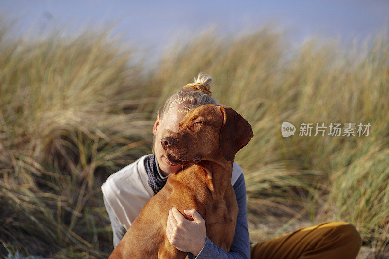 海滩上，一名女子抱着她的狗