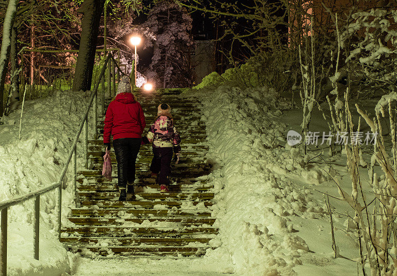 年轻女子，白种人，冬天带着一个七岁的小女孩在街上。一家人晚上很晚才回家。