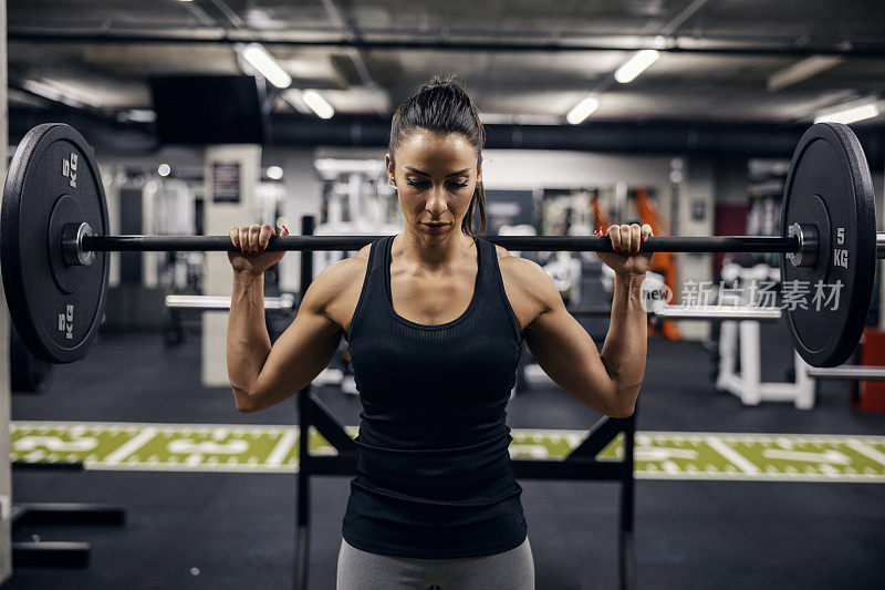 一个肌肉强壮的女健美运动员在健身房举重的肖像。