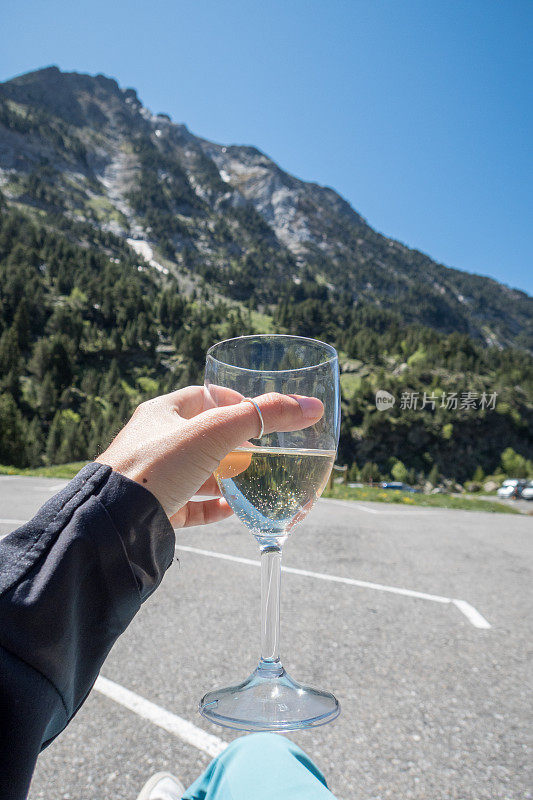 一辆露营车外的女子手持一杯白葡萄酒