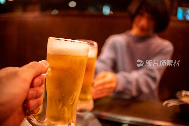 年轻女子在日本居酒屋酒吧用啤酒敬酒