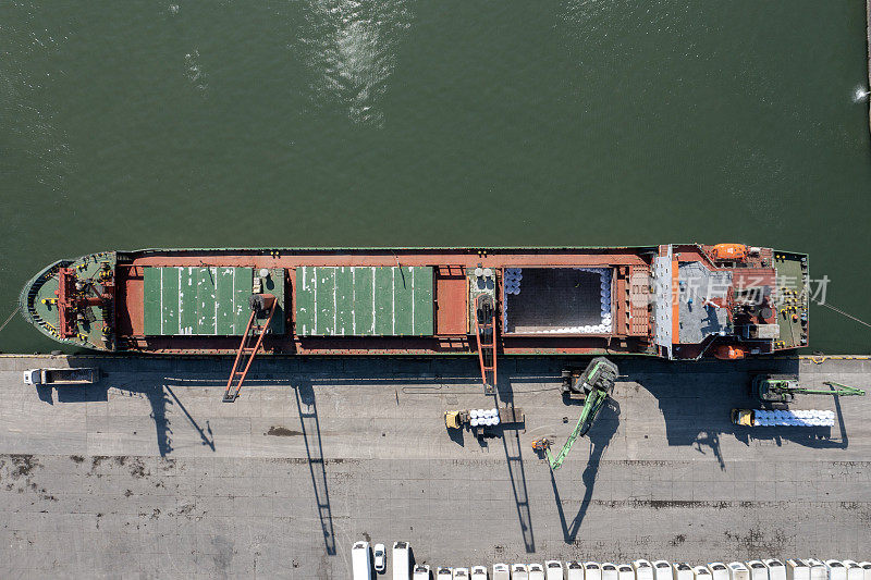 图为起重机将一袋袋的原材料装载到一艘国际货船上进行进出口