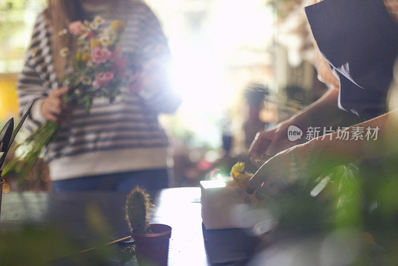 一个花店工人的手在小生意上给礼物打蝴蝶结的特写