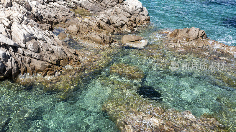 鸟瞰图的岩石海岸线沐浴在绿松石，清澈的水。意大利撒丁岛