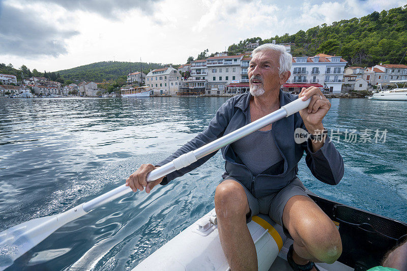 在克罗地亚的亚得里亚海上，一位年长的绅士花了很大的力气划着一只小橡皮艇。