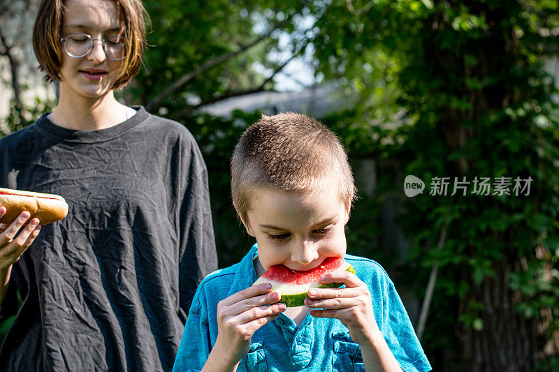 庆祝家庭团聚:性别不一致的青少年和弟弟分享美味的后院大餐