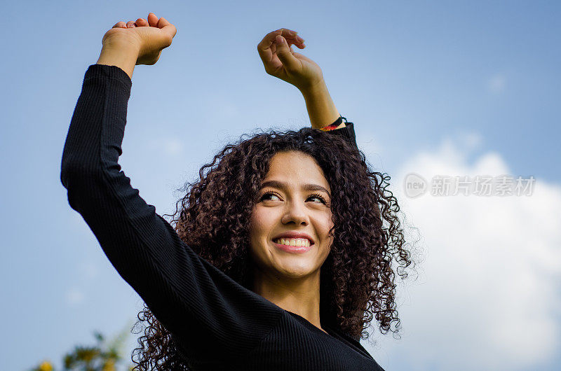 美丽的年轻白人女人，在蓝天的背景下有着一头卷发