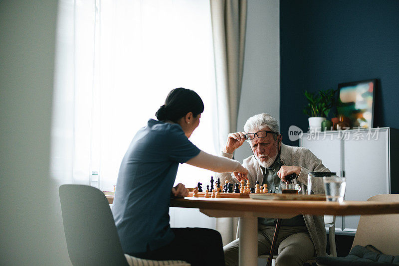 忧心忡忡的老人在客厅和一位匿名护士下棋