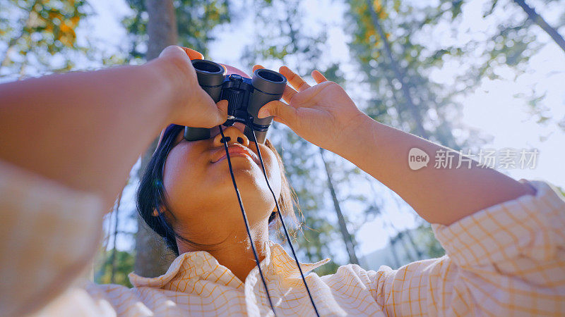 好奇，有趣和顽皮的孩子用双筒望远镜向外看，在自然公园，后院观察鸟类和野生动物。