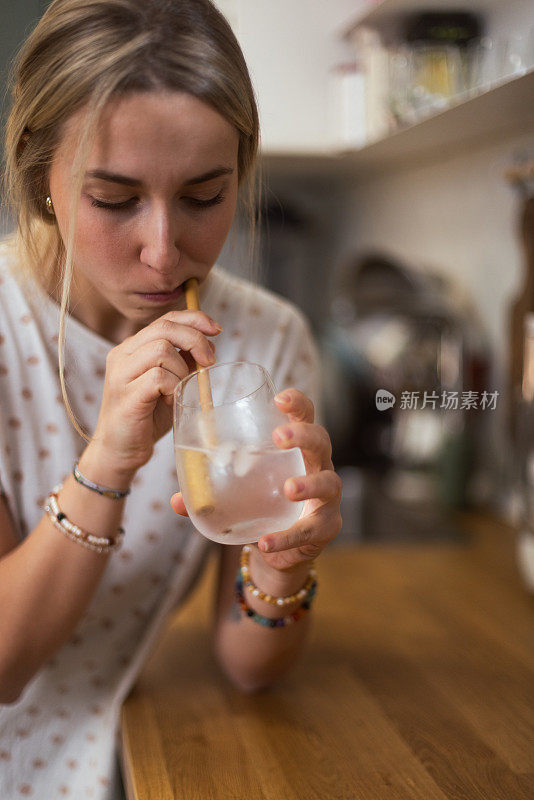 一个女人在家喝凉水，检查牙齿对寒冷的敏感度