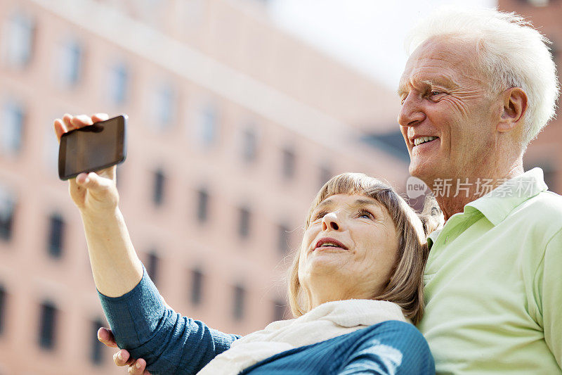 成熟的情侣用智能手机拍照