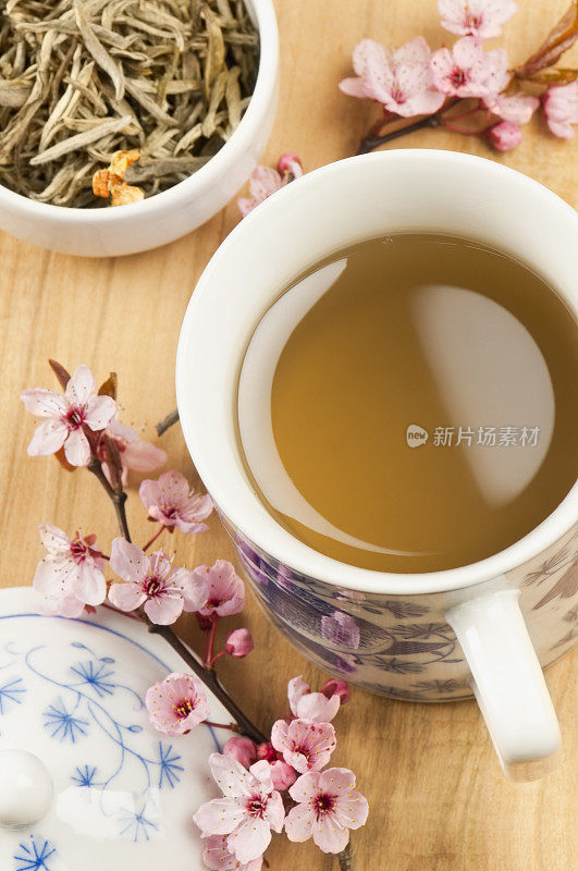 一杯茉莉花茶，有茶叶和粉红色的花朵