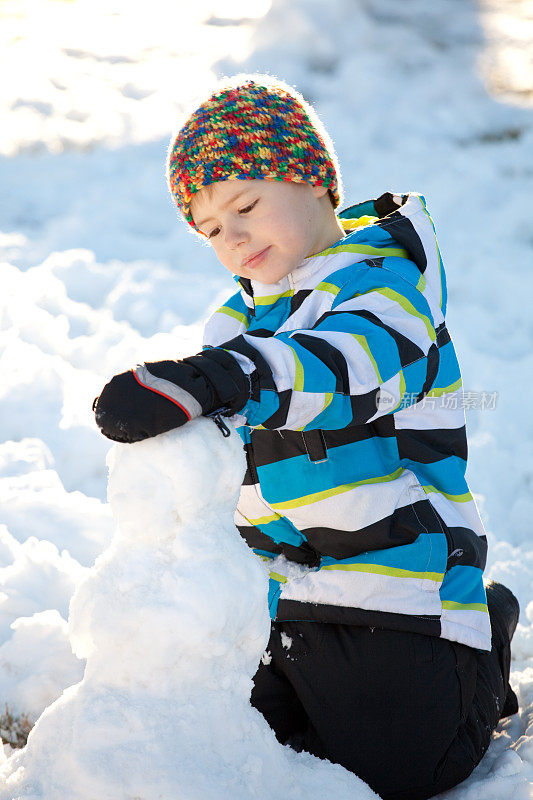 一个小男孩在外面堆雪人