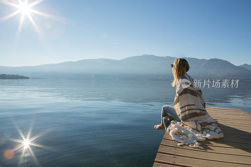 年轻女子在湖边码头上休息，看风景