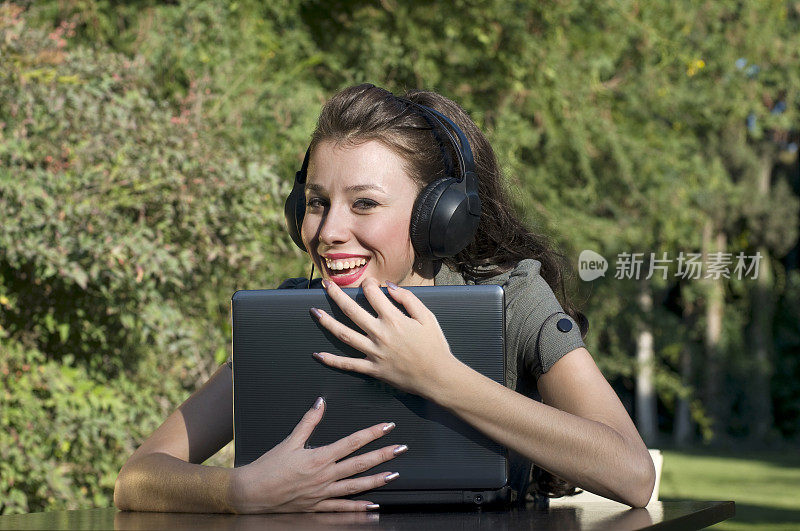 带着耳机和笔记本电脑的快乐女孩