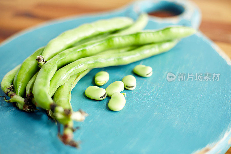 切菜板上的绿蚕豆和豆荚的特写