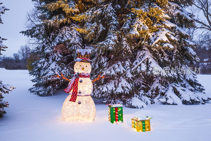 在白雪覆盖的松树间，堆着圣诞礼物的雪人。
