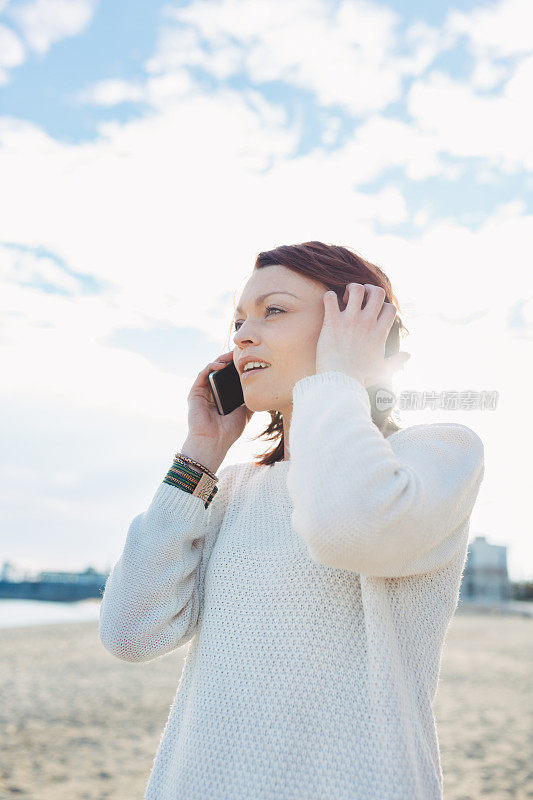 年轻女子在海滩上拿着智能手机