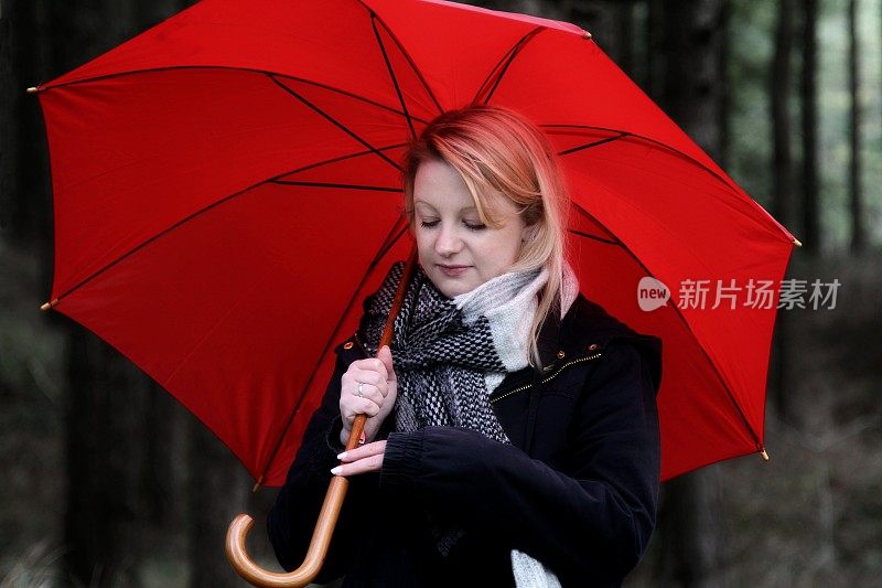 年轻女子穿着冬装，打着红伞