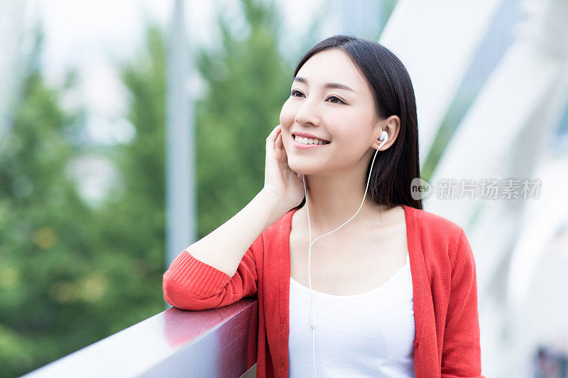 年轻女孩用智能手机的耳机听音乐