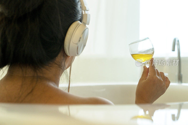 在浴缸里喝香槟听音乐的女孩
