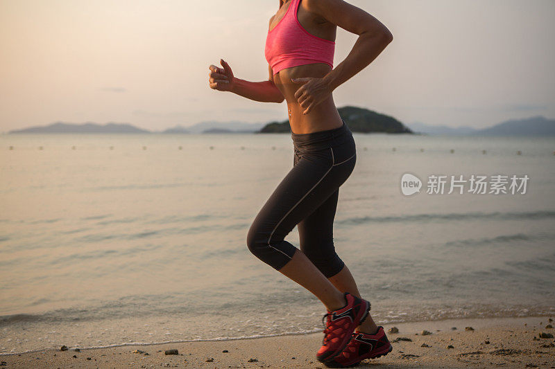 一个健康的年轻女子在热带海滩上跑步