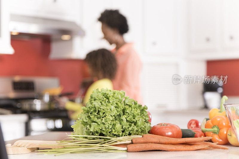 祖母或母亲和女儿一起在家里厨房做饭。