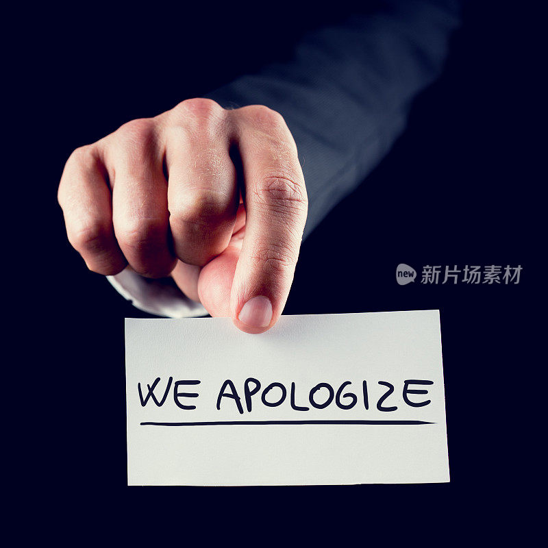 商人拿着一张写着“我们道歉”的卡片