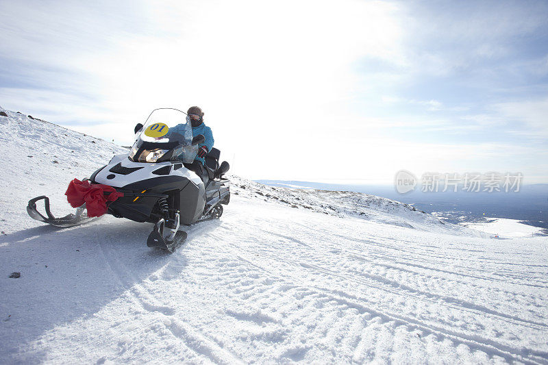 人们在冬天的山上骑雪上摩托
