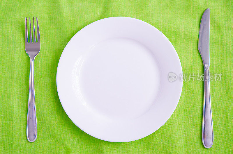 空盘子，叉子和刀在绿色的背景