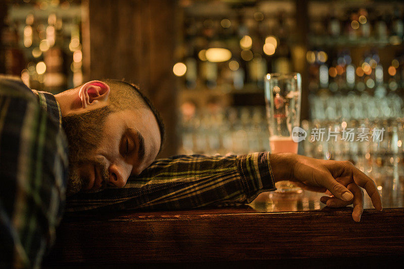 年轻的醉鬼们在一家酒吧的吧台上睡着了。