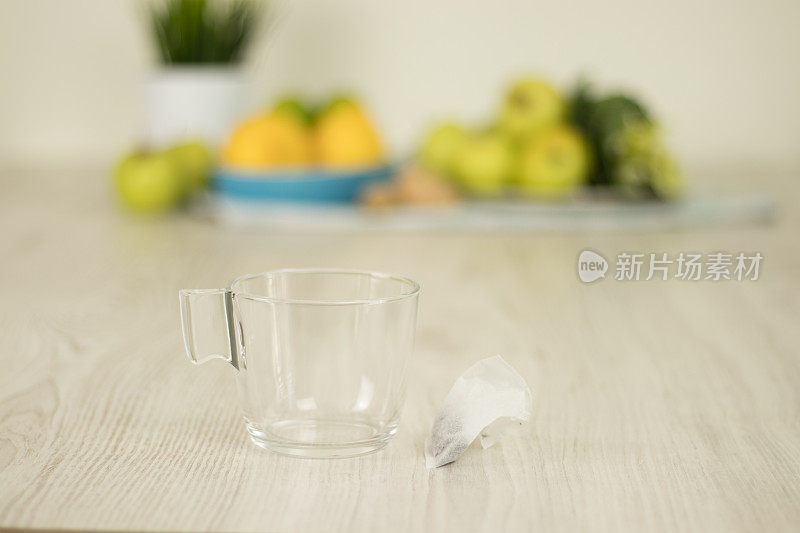 白色木桌上的茶杯上有模糊的水果背景。茶准备原料。