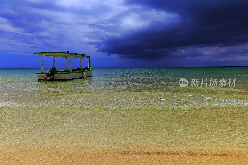 拖网渔船经过海滩与暴风雨云在地平线-内格里尔-牙买加，加勒比