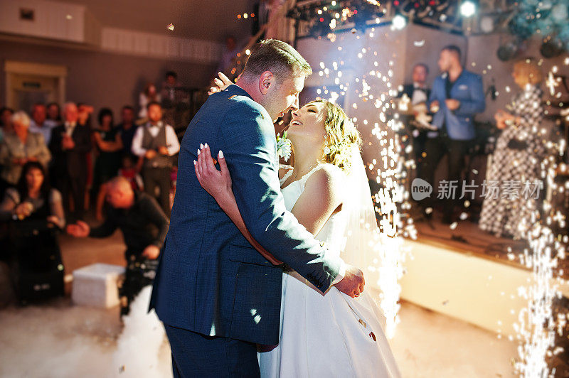 新婚夫妇在他们的婚礼上以浓烟、彩灯和烟火为背景跳舞。